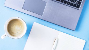 Laptop ve defter üzerinde mavi bir arka plan ile yaratıcı çalışma alanı