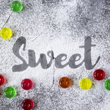 Word tatlı yanındaki renkli şeker pudra şekeri yardımıyla bir gri beton zemin üzerine yazılır. Üstten Görünüm, düz yatıyordu