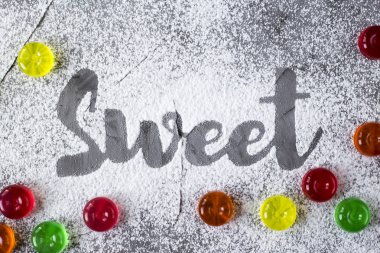 Word tatlı yanındaki renkli şeker pudra şekeri yardımıyla bir gri beton zemin üzerine yazılır. Üstten Görünüm, düz yatıyordu