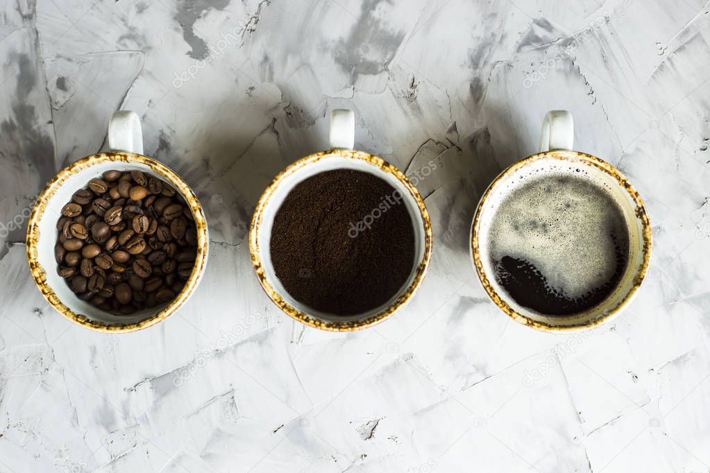 Three cups of coffee at different stages of cooking. Ground coffee, coffee beans and ready-made coffee drink. Top view, flat lay