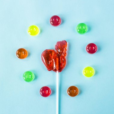 Bir horoz renkli şekerler - bir kupa şeklinde kırmızı lolipop retro tatlılar. Mavi arka plan üzerinde. Üstten Görünüm, düz yatıyordu