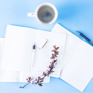 Yaratıcı bir iş ortamı üzerinde üç defter çiçekli dallar üzerinde mavi bir arka plan ile bir yığın