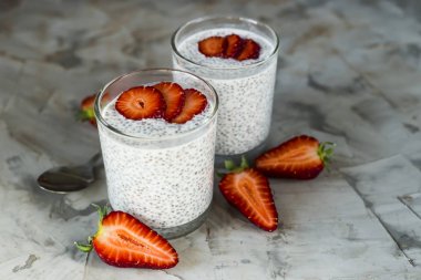 İki porsiyon tatlı chia tohum, süt ve çilek gri bir tablo yapılır. Sağlıklı kahvaltı konsepti