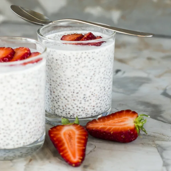 İki porsiyon tatlı chia tohum, süt ve çilek gri bir tablo yapılır. Sağlıklı kahvaltı konsepti