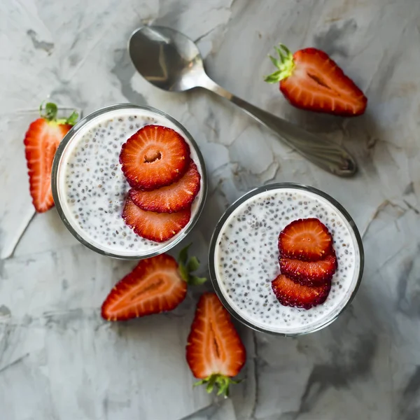 İki porsiyon tatlı chia tohum, süt ve çilek gri bir tablo yapılır. Sağlıklı kahvaltı kavramı. Üstten Görünüm