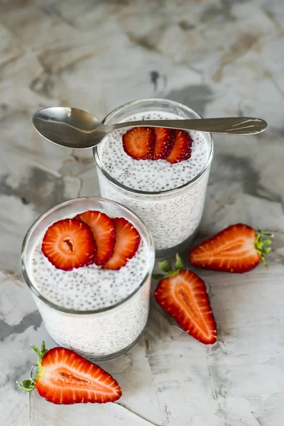 İki porsiyon tatlı chia tohum, süt ve çilek gri bir tablo yapılır. Sağlıklı kahvaltı kavramı. Üstten Görünüm