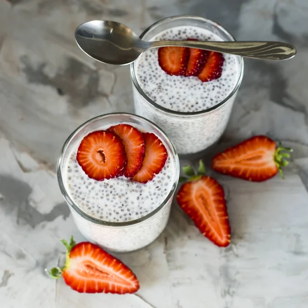 İki porsiyon tatlı chia tohum, süt ve çilek gri bir tablo yapılır. Sağlıklı kahvaltı kavramı. Üstten Görünüm
