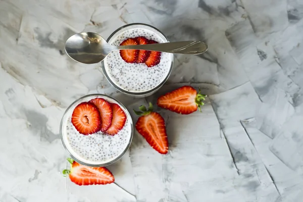 İki porsiyon tatlı chia tohum, süt ve çilek gri bir tablo yapılır. Sağlıklı kahvaltı kavramı. Üstten Görünüm