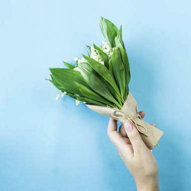 Zambak vadi içinde erkek bir buket mavi bir arka plan üzerinde eller. Üstten Görünüm, düz yatıyordu