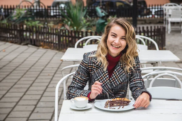 Caucasian happy girl drinks coffee at a table of a street coffee shop. — Stock Photo, Image