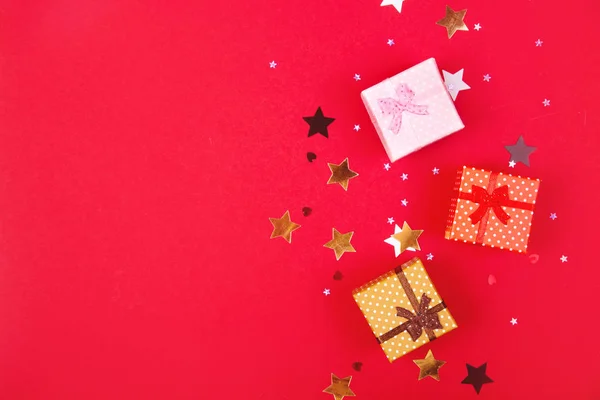 Drie geschenken met glanzende sterren rond op rood. — Stockfoto