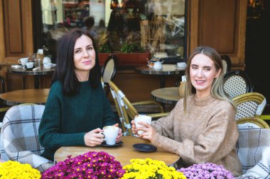 İki neşeli bayan arkadaş, şehirdeki bir kafede cappuccino içiyor..