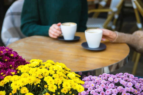Două fete beau cappuccino într-o cafenea aproape de mâini . — Fotografie, imagine de stoc