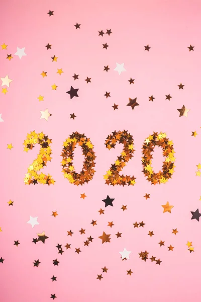 2020 Simbol tahun baru emas confetti di tanah merah muda . — Stok Foto