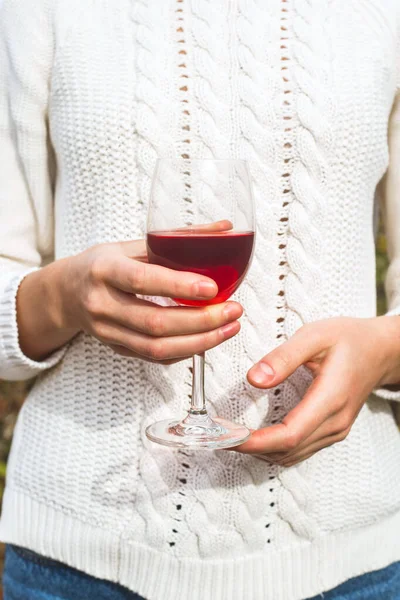 Szklanka czerwonego wina domowego w rękach kobiety w białym swetrze. — Zdjęcie stockowe
