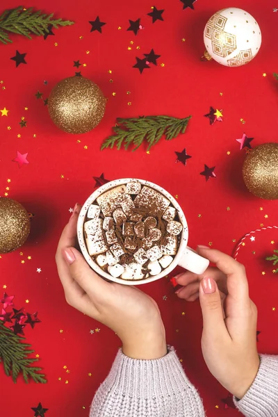 Kırmızı üzerine Noel süslemeleri arasında kadın ellerinde lokum olan kakao..