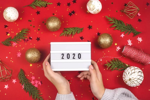 Las manos femeninas sostienen un ornamento rectangular con inscripción 2020. Concepto de año nuevo . —  Fotos de Stock
