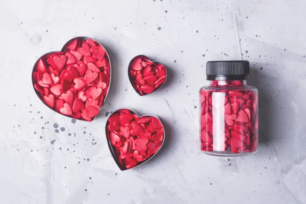 Los corazones rojos como símbolo del polvo de confitería del Día de San Valentín sobre un fondo de hormigón gris . — Foto de Stock