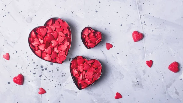 Corações vermelhos como um símbolo do Dia dos Namorados pó de confeitaria em um fundo de concreto cinza . — Fotografia de Stock