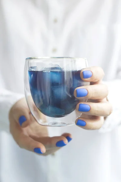 Vrouw met klassieke blauwe manicure houdt een glas matcha blauwe thee — Stockfoto