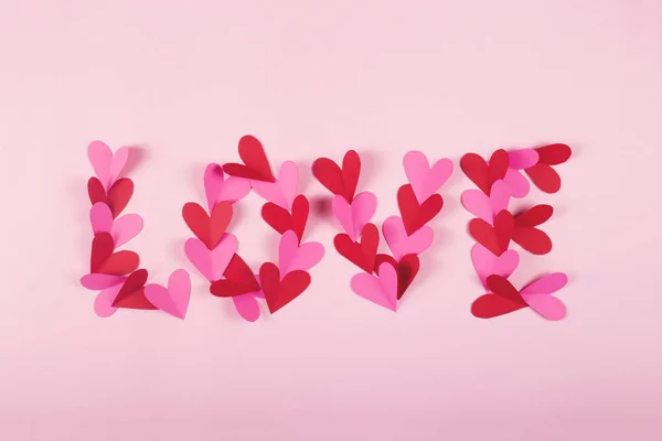 Word love made of paper hearts on a pink background. — 스톡 사진