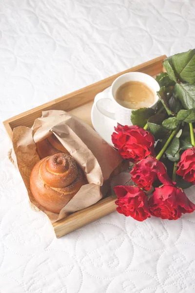 Café y magdalenas en una bandeja de madera. Con un ramo de flores en la cama . — Foto de Stock