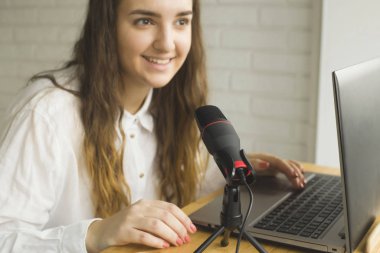 Bir blogcu ev içi bir mikrofona bir podcast kaydeder.