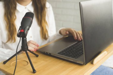 Bir blogcu ev içi bir mikrofona bir podcast kaydeder.