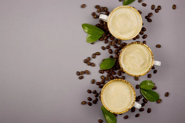 Café dans des tasses rustiques parmi les grains et les feuilles de café vert . — Photo