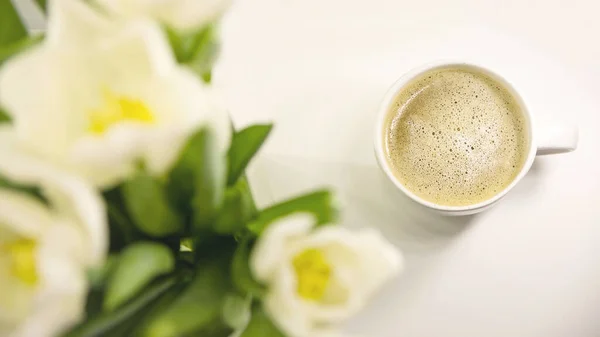 Filiżanka kawy rano obok bukietu białych tulipanów. Wiosenna karta wakacyjna. — Zdjęcie stockowe