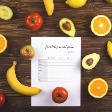 Tahta masada taze organik meyve ve sebzeler arasında sağlıklı haftalık yemek planı..