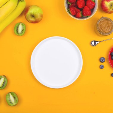 Beyaz tabak sağlıklı bir kahvaltı için sarı arka planda meyveler arasında.