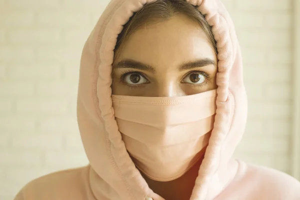 Chica en una máscara rosa para la protección contra 2019-ncov covid-19 en casa en aislamiento social . — Foto de Stock