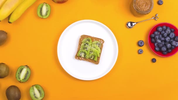 Sandwich mit Kiwi und Erdnussbutter auf gelb. — Stockvideo