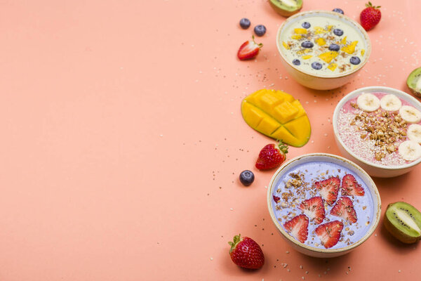 Vegetarian healthy food made from multi-colored smoothies with matches and berries on a bright pink background.