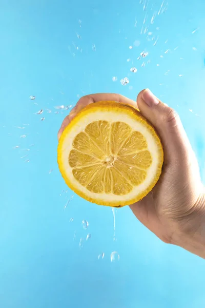 Limón amarillo en la mano con gotas de jugo — Foto de Stock