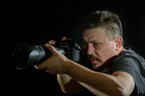 Fotógrafo de retrato com uma câmera em fundo preto — Fotografia de Stock