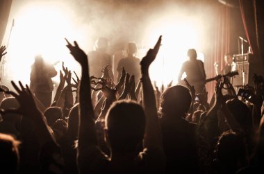parlak ışık sahne önünde bir konserde insan siluetleri