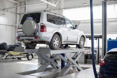 Mavi bir çalışma formu bir araba atölye bir mekanik çalışan bir gri araba onarıyor. Oto servisi.