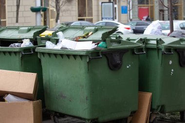 Bir apartmanın avlusunda tekerlekler üzerinde çöp dolu yeşil tanklar