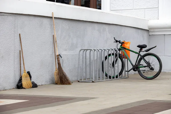 Σκούπες Και Σκούπες Στον Τοίχο Και Ένα Παρκαρισμένο Μαύρο Ποδήλατο — Φωτογραφία Αρχείου