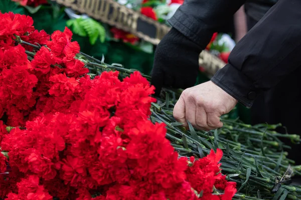 Röda nejlikor läggs på marmor minnesmärke till ära för dem som dödades i kriget — Stockfoto