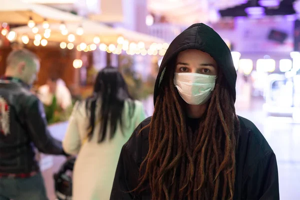 Ragazza in maschera medica a un cappuccio nero in un centro commerciale — Foto Stock