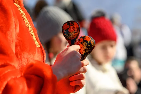 Geleneksel bir Rus aksesuarı olan tahta kaşıklar kırmızı folklor elbiseli bir kızın elinde. Karnaval festivali. Halk müziği enstrümanı. Tahta kaşıklarla oyna