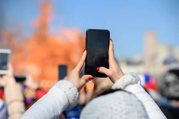 girl with red manicure shoots video on the phone. video for social networks from the carnival. man makes photo on smartphone