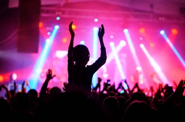 Pembe ışıkta sahnenin önünde alkışlayan bir kalabalığın silueti. Müzik festivali afişi. Yaklaşan gösterinin afişi.