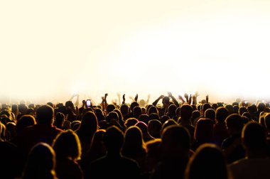 Bir müzik festivali konserinde el kaldıran kalabalık. Sahnenin önünde bir sanatçıyla insanların siluetleri. gece diskosu