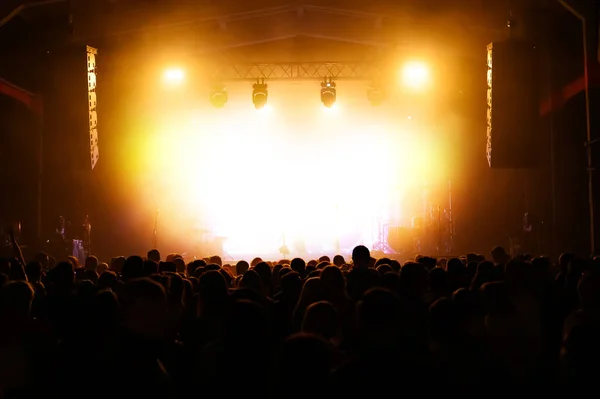 Bir konser festivalinde kalabalık sahnede bir sanatçıyı bekliyor. Müzik şovu afişi. Sahne ve insanların sırtı aydınlandı.