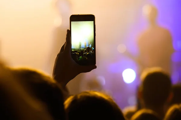 hand with smartphone from the crowd at a music concert. shoot a video of your favorite song at a concert. banner for the show.