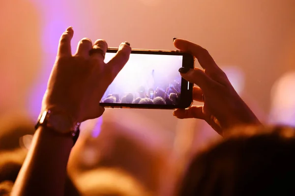 Record a concert from a mobile phone, silhouette of a hand from a smartphone. Take a concert in front of the stage